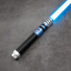 Blue and silver saber hilt with black ribbed grip, ignited with a blue blade on a concrete surface.