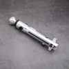 A silver Snips CW shoto saber hilt by Laser Monkey Sabers, featuring a minimalist design with black buttons and a rounded pommel, resting on a gray concrete surface.
